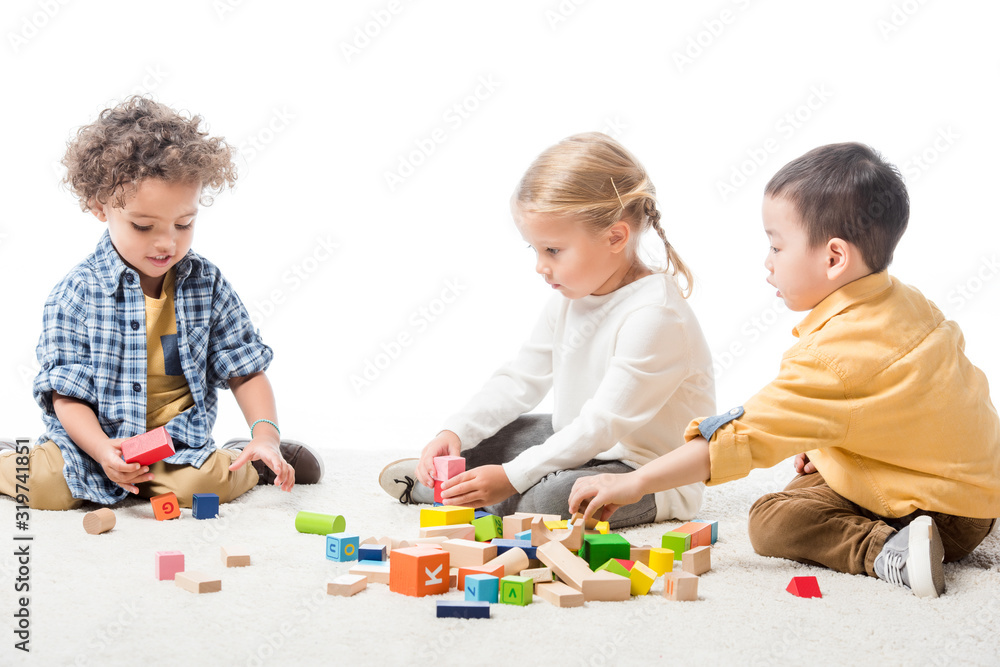 multicultural kids playing with wooden blocks on carpet, isolated on white multicultural kids playing with wooden blocks on carpet, isolated on white