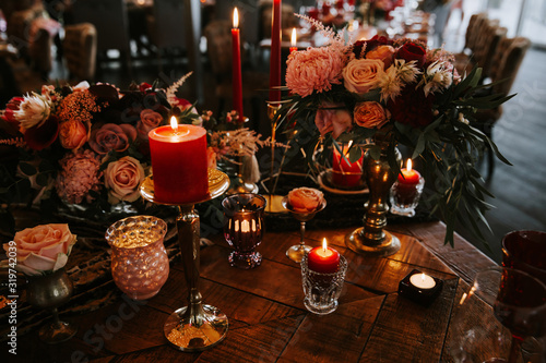 Romantic red table, decorated table with flowers and red candles. Luxury Christmas evening or wedding party decoration.