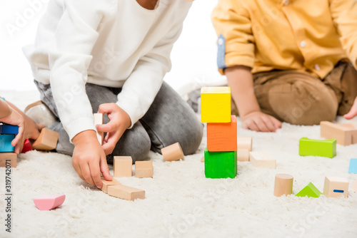 cropped view of kids playing with wooden blocks on carpet