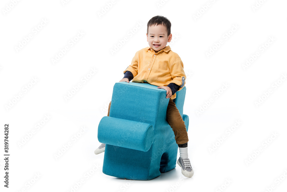 smiling asian boy sitting on blue puzzle chair isolated on white smiling asian boy sitting on blue puzzle chair isolated on white