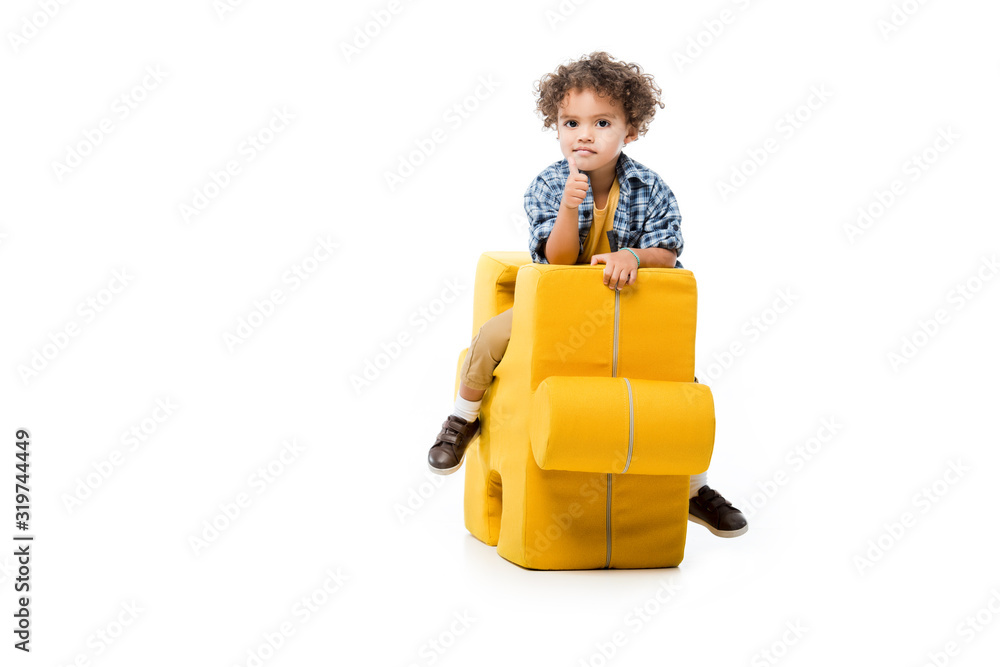 little african american boy showing thumb up and sitting on yellow puzzle chair, isolated on white little african american boy showing thumb up and sitting on yellow puzzle chair, isolated on white