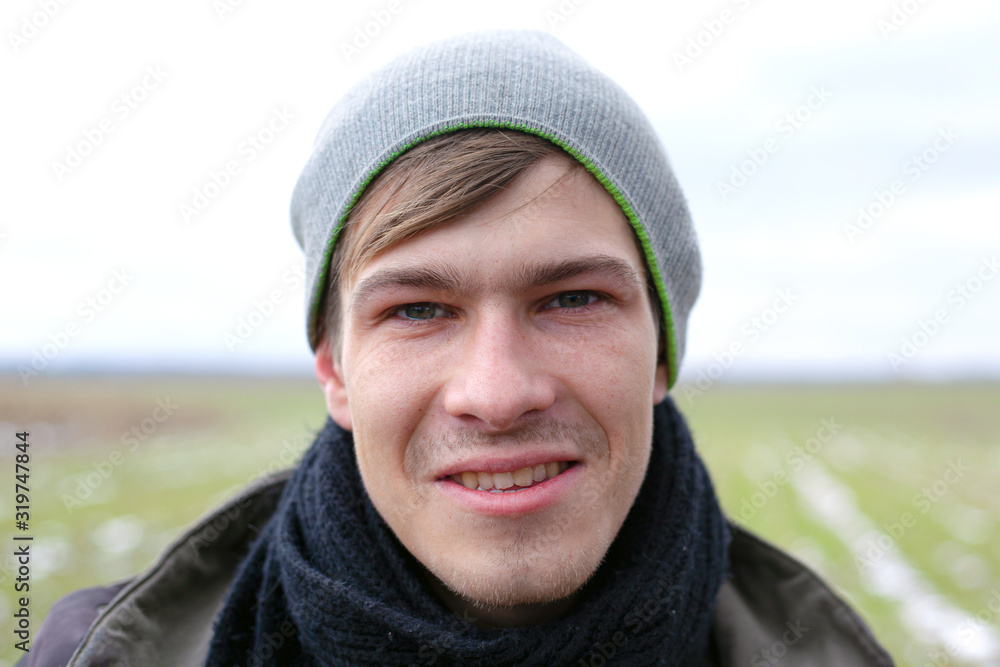 young handsome unshaven guy close-up face portrait on a spring field background with green grass
