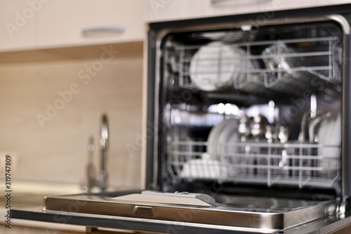  A dishwasher with open dishes at the sink level with a dryer and two taps, as a blurred background with bokeh.