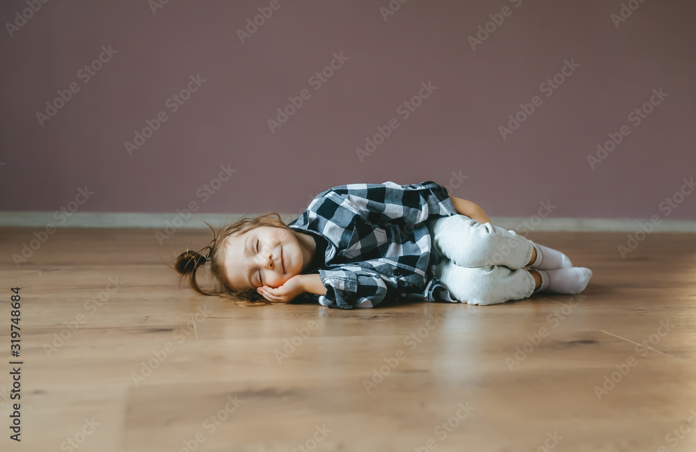 Funny portrait of lying sleep little girl on a floor indoors