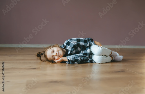 Obraz na płótnie Funny portrait of lying sleep little girl on a floor indoors w salonie