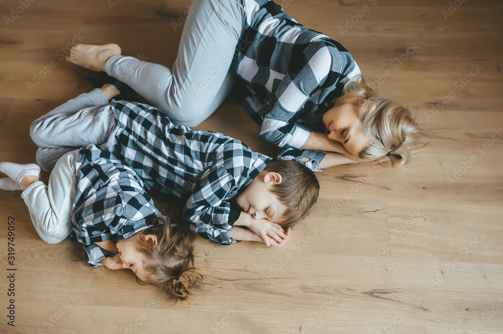 Top view of mother and her two kids in identical clothes lying on floor with closed eyes. Top view