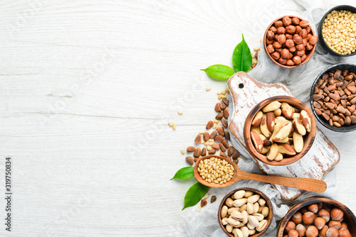 Assortment of nuts in bowls on white wooden background. free space for your text. Top view.