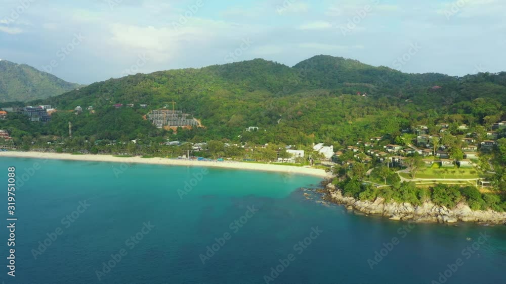 Aerial panorama of tropical resort territory and beach, beautiful Andaman sea at west coast of Phuket Island. Kata Noi beach from above, some buildings and green hills, calm sea surface to horizon Aerial panorama of tropical resort territory and beach, beautiful Andaman sea at west coast of Phuket Island. Kata Noi beach from above, some buildings and green hills, calm sea surface to horizon