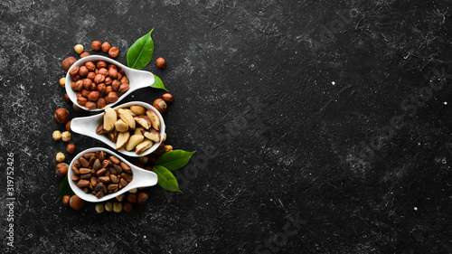 Assortment of nuts: pistachios, hazelnuts, pine nuts on a black stone background. free space for your text. Top view.