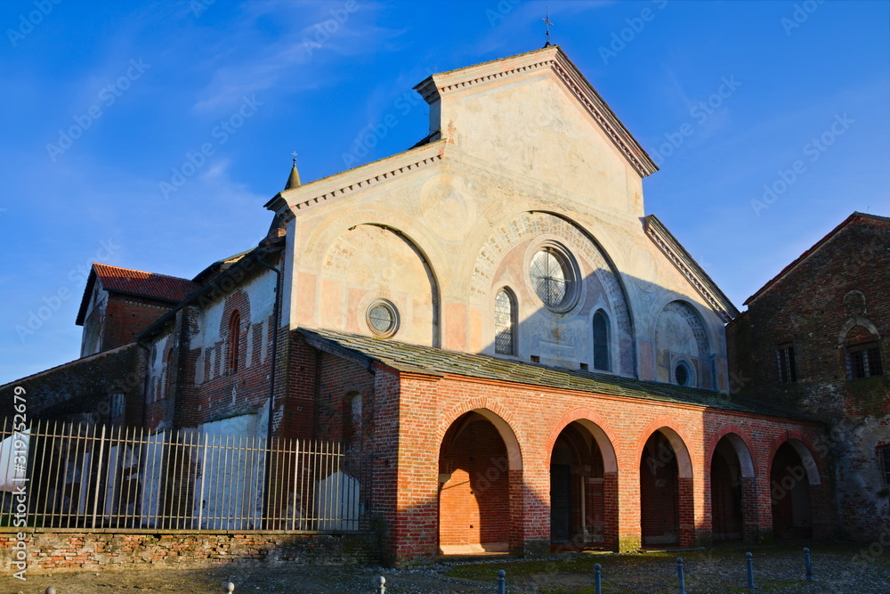 Revello, Piedmont, Italy - January 12, 2020: Facade of the Staffarda abbey, a Cistercian monastery located near Saluzzo, founded in 1135, seen at sunset in a blue sky sunny winter day