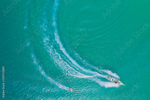 Aerial drone photo of extreme powerboat donut water-sports cruising in high speed in tropical turquoise bay. Thailand, Phuket, Kata beach © netsay