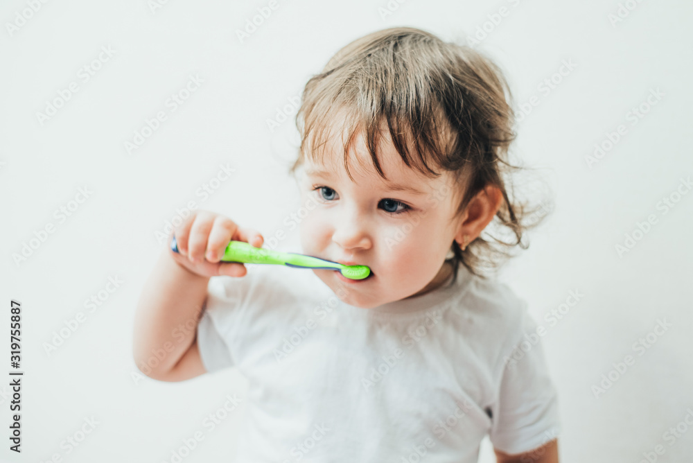 Little girl brushes her teeth with a toothbrush on a light background Little girl brushes her teeth with a toothbrush on a light background