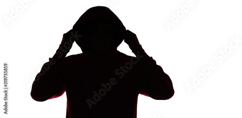 dark male silhouette in casual sportswear with a hood, figure of a guy hiding his face, concept of privacy and confidentiality photo