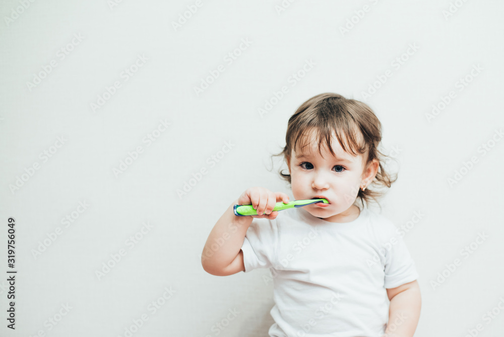 Little girl brushes her teeth with a toothbrush on a light background Little girl brushes her teeth with a toothbrush on a light background