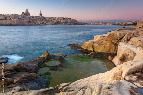 Rocky coastline of Malta and beautiful architecture of the Valletta city at dawn