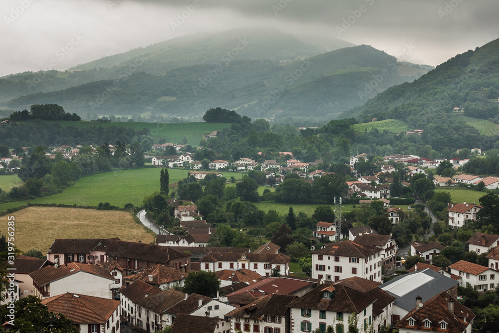 The small town of Saint-Jean-Pied-de-Port in the French Pyrenees. The beginning of the way of St. James. French village in the mountains. Green forests and tiled brown roofs of old houses.