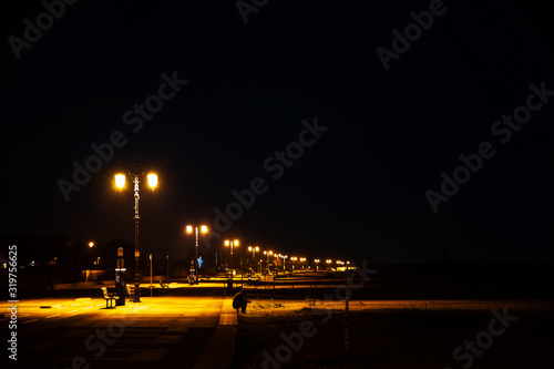 England, Nachts an der Küste von Portsmouth, Ein Mann sitzt am Strand.