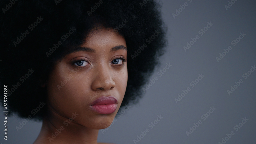 Portrait of wonderful nude black young woman with afro hairstyle looking straight against grey background. Pretty african girl posing on camera. Portrait of wonderful nude black young woman with afro hairstyle looking straight against grey background. Pretty african girl posing on camera.
