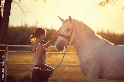Horse getting pets by girl rider.  Fun on countryside, sunset golden hour. Freedom nature concept.