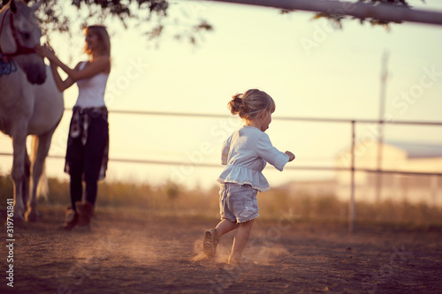 Little girl running around on the ranch. Fun on countryside, sunset golden hour. Freedom nature concept.