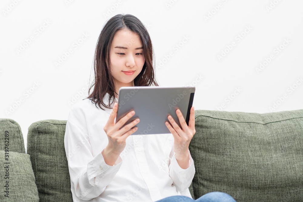 リビングでタブレットを操作する女性 リビングでタブレットを操作する女性