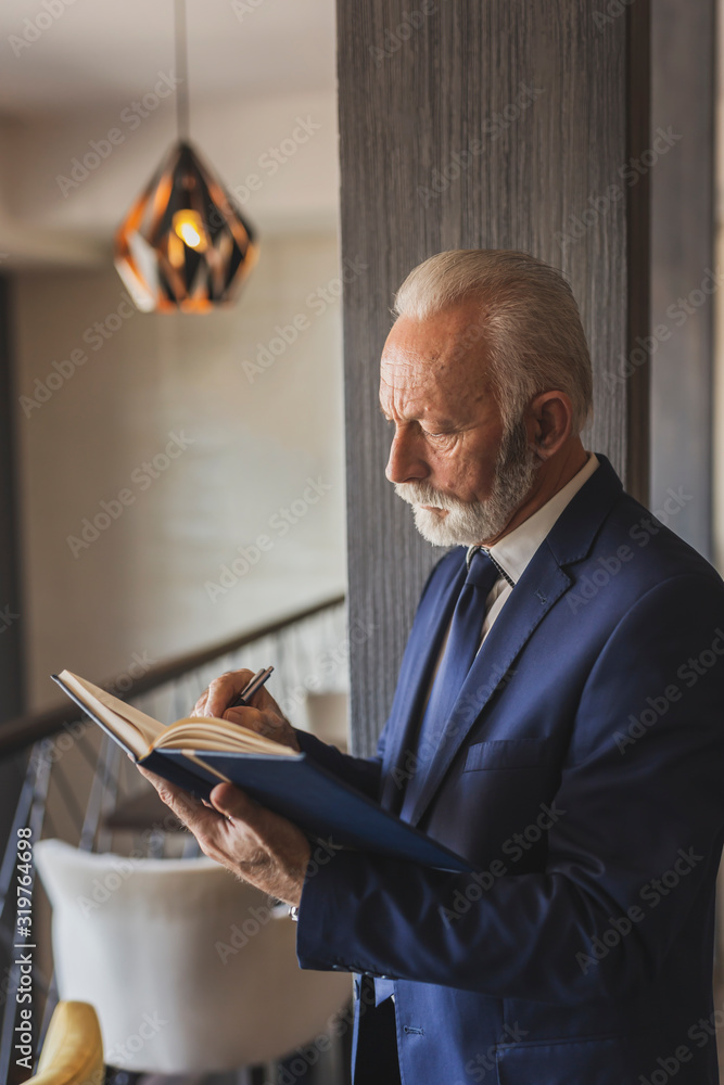 Fototapeta premium Senior businessman writing in a planner