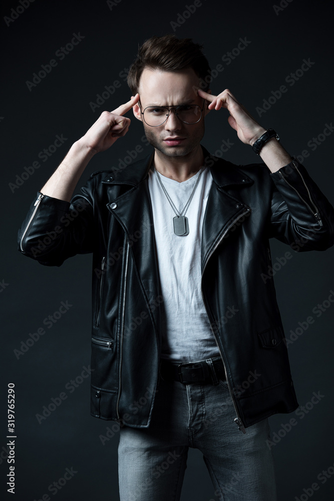 pensive stylish brutal man in biker jacket isolated on black