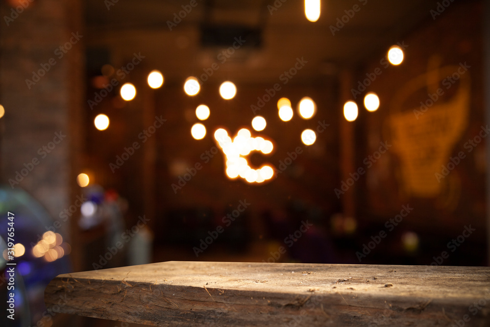 Blurred cafe bar, restaurant, club, blurred light golden bokeh background. With wooden tables in focus.