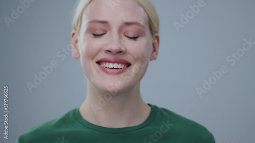 Fotografie Portrait of beautiful young blonde woman crying of happiness with tears smiling on camera in the studio on grey background