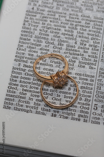 Wedding rings lie on the page of an open Bible. In the center of the ring the phrase is visible: God is Love.