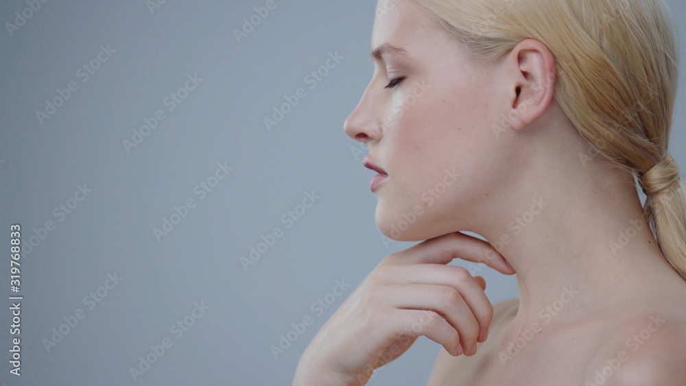 Profile of amazing blonde girl with naked shoudlers isolated on gray. Close-up of gorgeous young woman smiling cheerfully while posing in the studio. Profile of amazing blonde girl with naked shoudlers isolated on gray. Close-up of gorgeous young woman smiling cheerfully while posing in the studio.