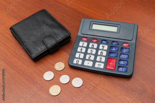 Wallet, calculator and coins on a wooden texture.