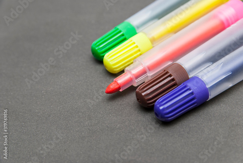 Multi-colored felt-tip pens close-up on a gray background.