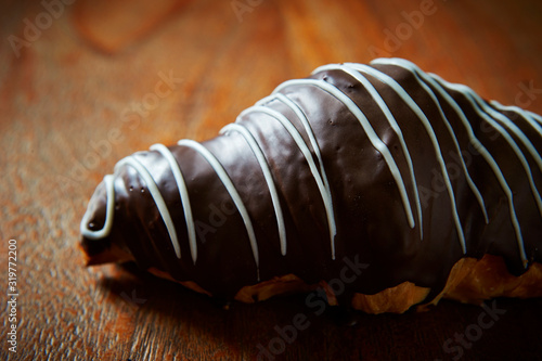 Chocolate coated croissant on wooden background 