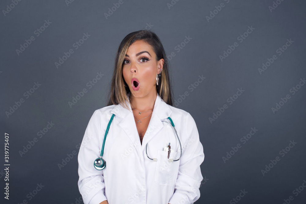 Attractive young doctor woman having stunned and shocked look, with jaw dropped, listening to friend's story in full disbelief, exclaiming: Wow, I can't believe this. Surprised girl. Shock Attractive young doctor woman having stunned and shocked look, with jaw dropped, listening to friend's story in full disbelief, exclaiming: Wow, I can't believe this. Surprised girl. Shock