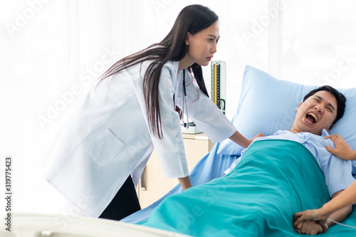 Two doctors holding a psycho patient on bed in hospital