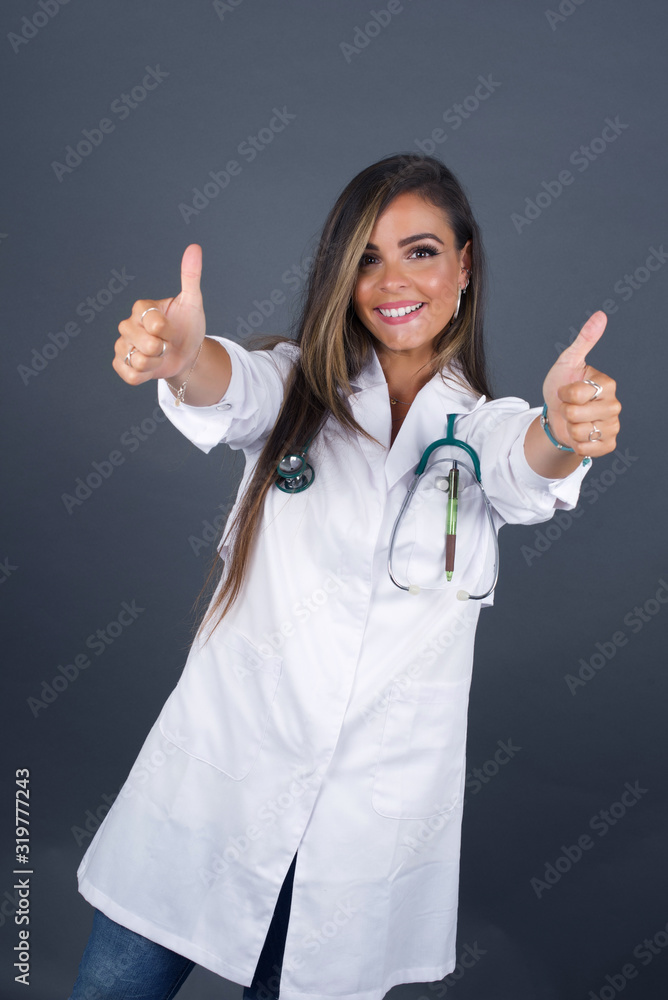 Good job! Portrait of a happy smiling doctor young successful woman giving two thumbs up gesture standing indoors. Positive human emotion facial expression body language. Funny girl Good job! Portrait of a happy smiling doctor young successful woman giving two thumbs up gesture standing indoors. Positive human emotion facial expression body language. Funny girl