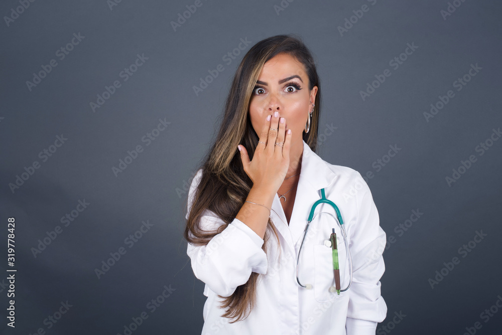 Oh! I think I said it! Close up portrait of doctor lady in white, covers open mouth by hand palm, looks at camera with big eyes isolated on bright mint background. Oh! I think I said it! Close up portrait of doctor lady in white, covers open mouth by hand palm, looks at camera with big eyes isolated on bright mint background.