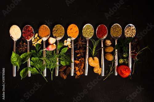 Fototapeta Naklejka Na Ścianę i Meble -  A set of spices and herbs. A lot of seasoning in spoons on black background