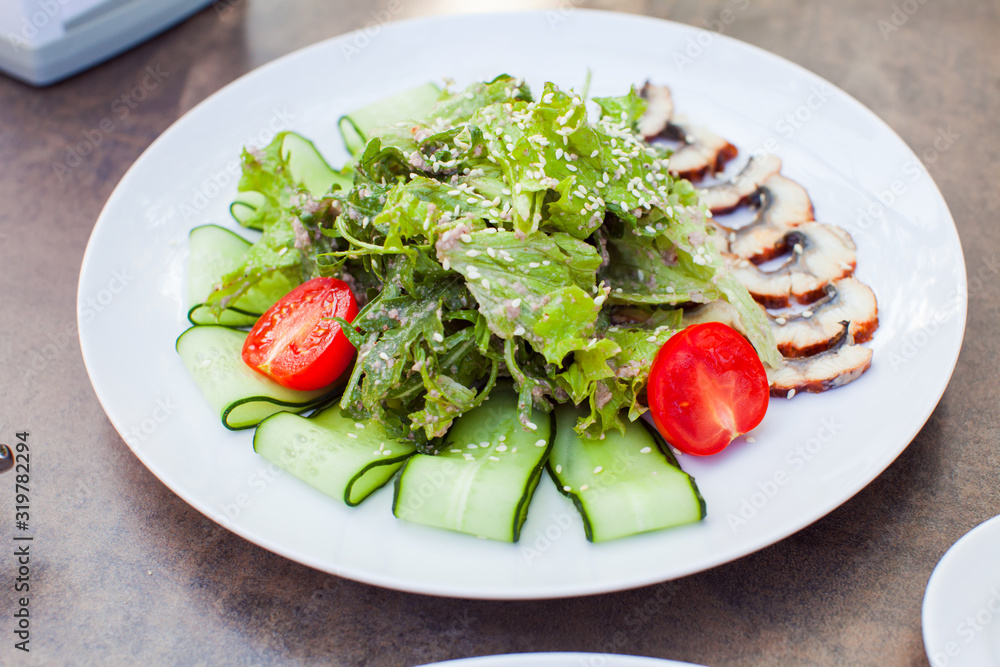 Closeup of a tasty fresh eel salad with arugula, lettuce and tomatos on white plate Closeup of a tasty fresh eel salad with arugula, lettuce and tomatos on white plate