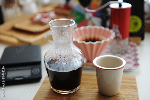 Manual brewing still life. Pouring filter coffee is served in decanter on bamboo board. Third wave specialty aesthetics