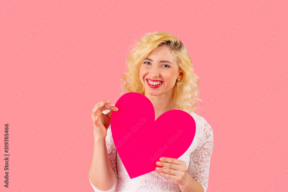 Studio portrait of a smiling young woman holding pink heart, romantic love, dating and Valentine's Day concept with copy space Studio portrait of a smiling young woman holding pink heart, romantic love, dating and Valentine's Day concept with copy space