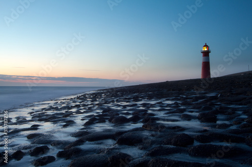 lighthouse on Zeeland in the Netherlands at blue hour with shore and North Sea