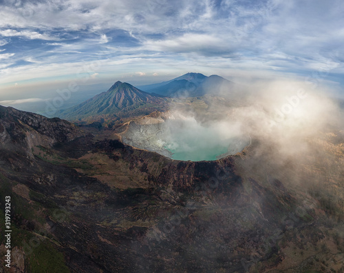 Spectacular aerial view of Mount Ijen volcano on East Java with sulfur blue acid lake and smoke erupting from the crater