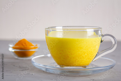 Golden milk in a glass gray cup on a gray background