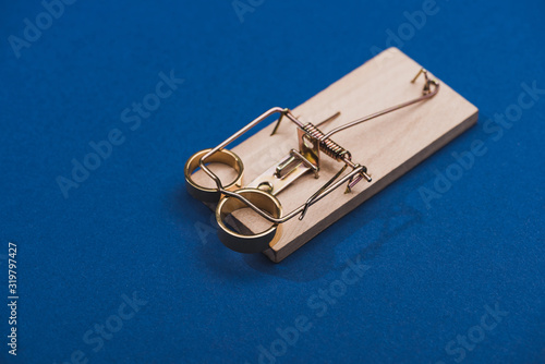 Two golden jewellery rings in mouse trap on blue background photo