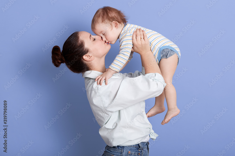 Horizontal shot of mom throws baby and kiss his, playing together and