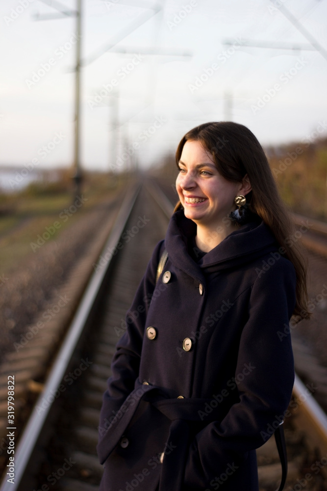 Girl walks on railway rails in a coat - travel, lifestyle Girl walks on railway rails in a coat - travel, lifestyle