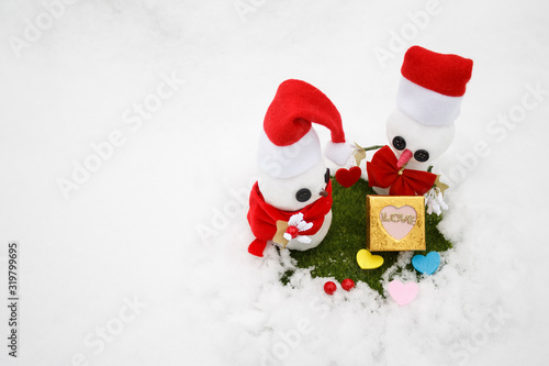 Snowmen in love with gifts for Valentine's Day.Holiday concept. Copy space. Snowmen on the grass.