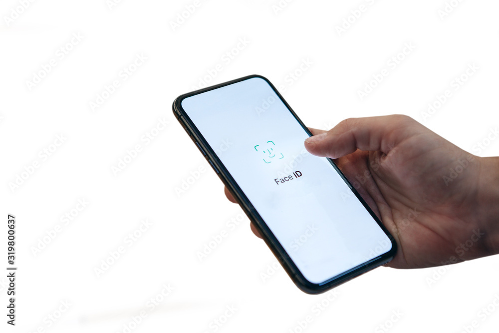 Person uses face id on cell phone. Hand with a phone on a white background